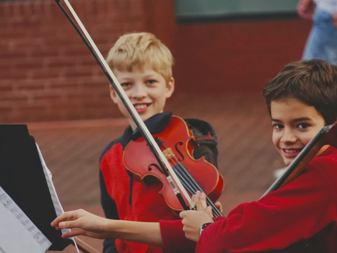 Two young string students smiling at a recital.